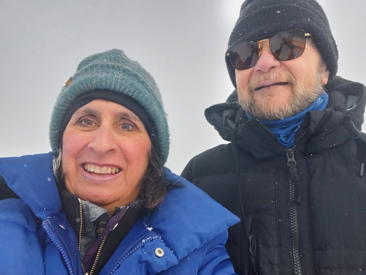 Bob and his wife smiling on a snowy winter hike, both in hats and heavy coats
